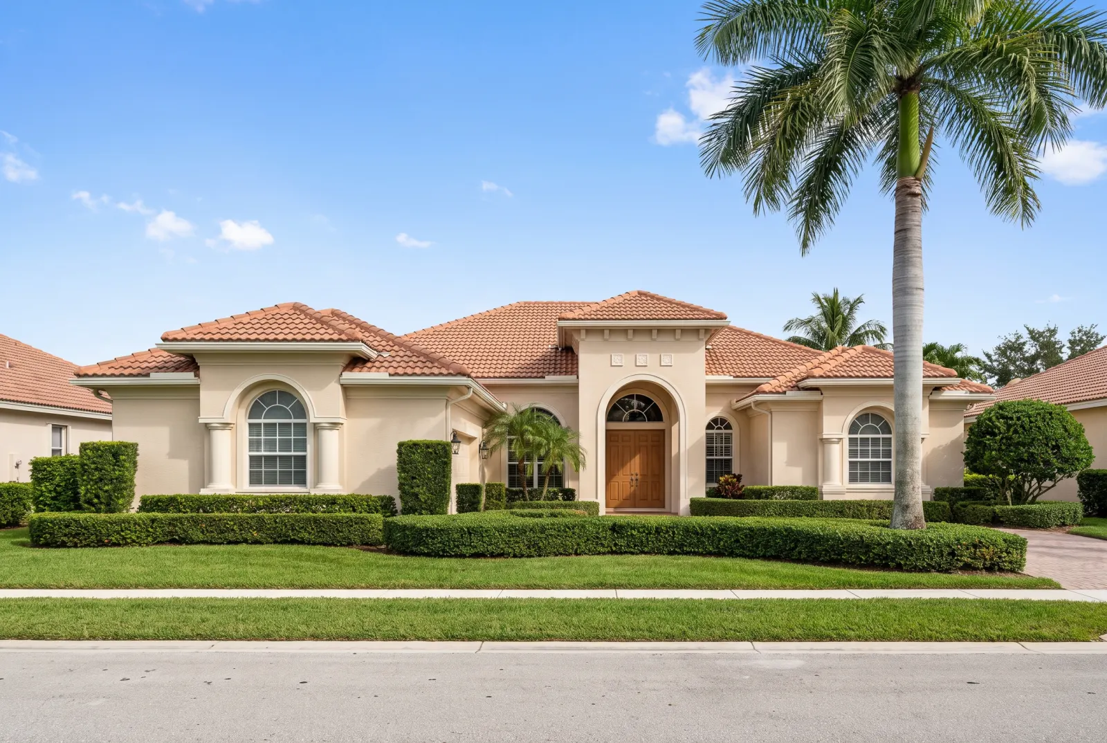 Beige stucco house with a tile roof on a sunny day