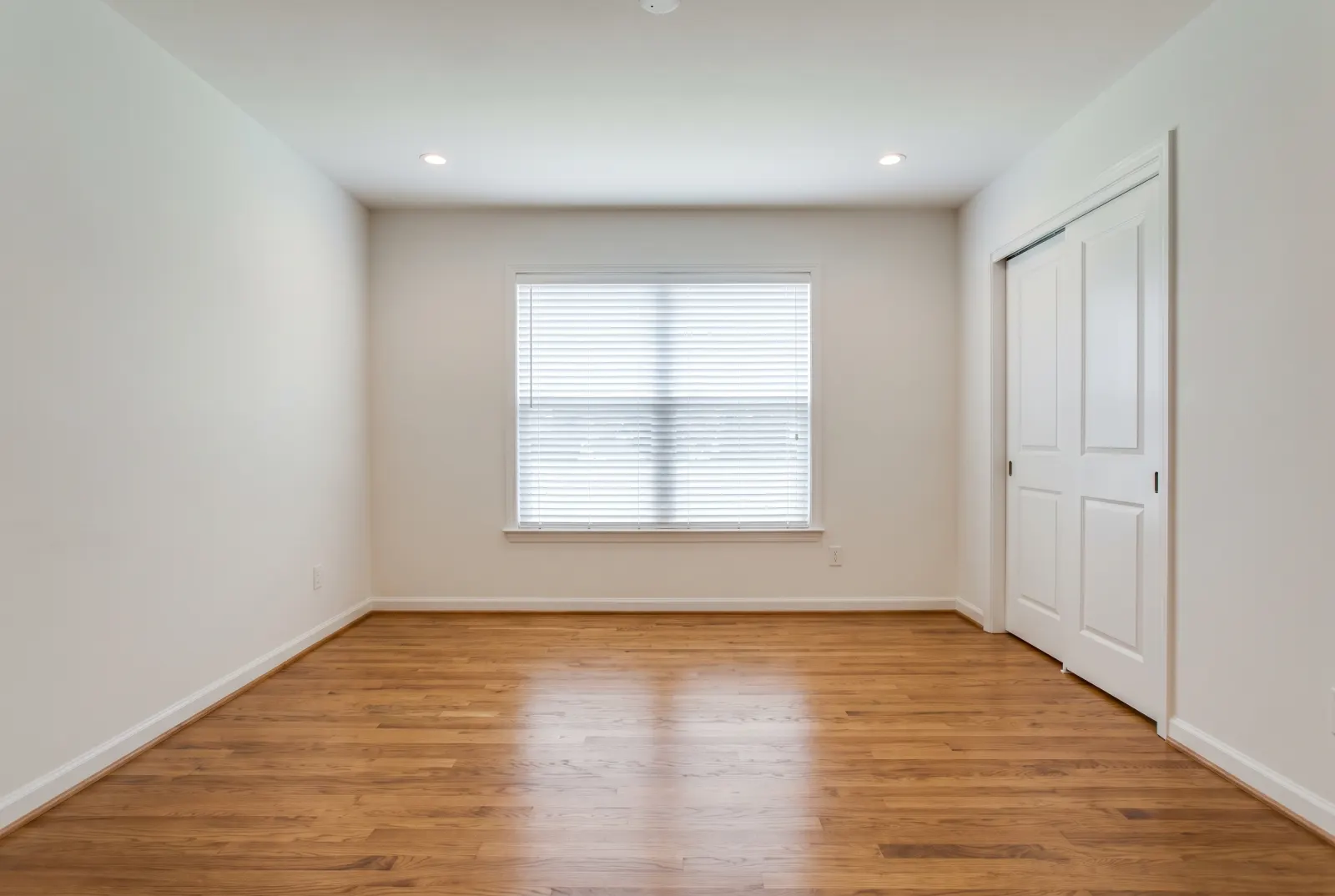 Empty bedroom with an oak floor and one window