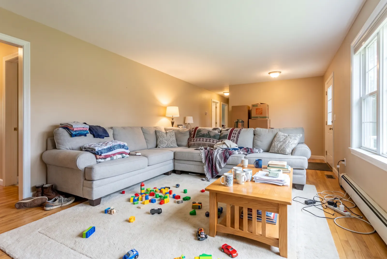 Cluttered family living room with toys, laundry and boxes